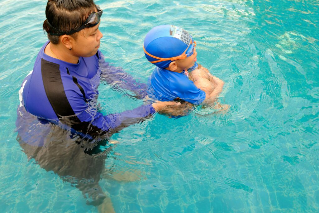A child and instructor in a swimming lesson at an outdoor pool.