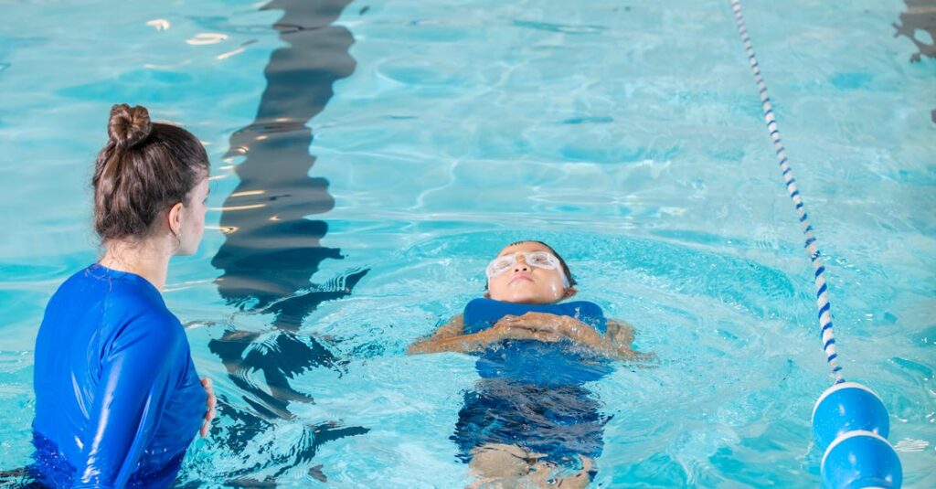 A swimming instructor teaches a young child to swim in an indoor pool.